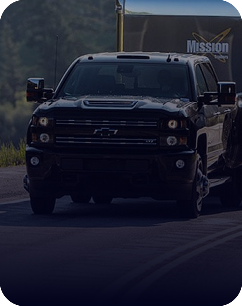 Black Chevy Silverado HD truck towing an enclosed cargo trailer.