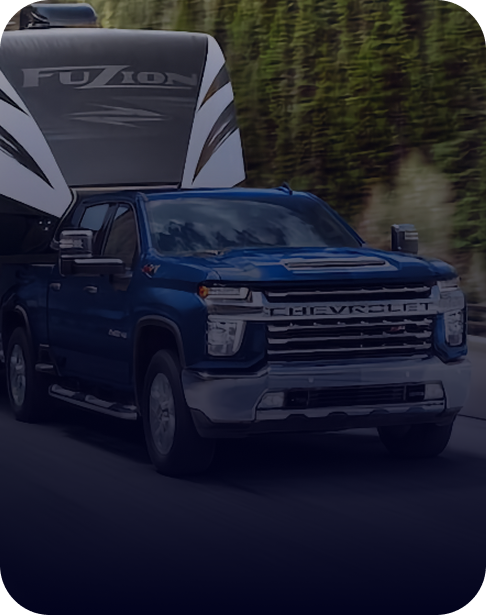 Blue heavy-duty Chevy Silverado towing a large fifth-wheel trailer.